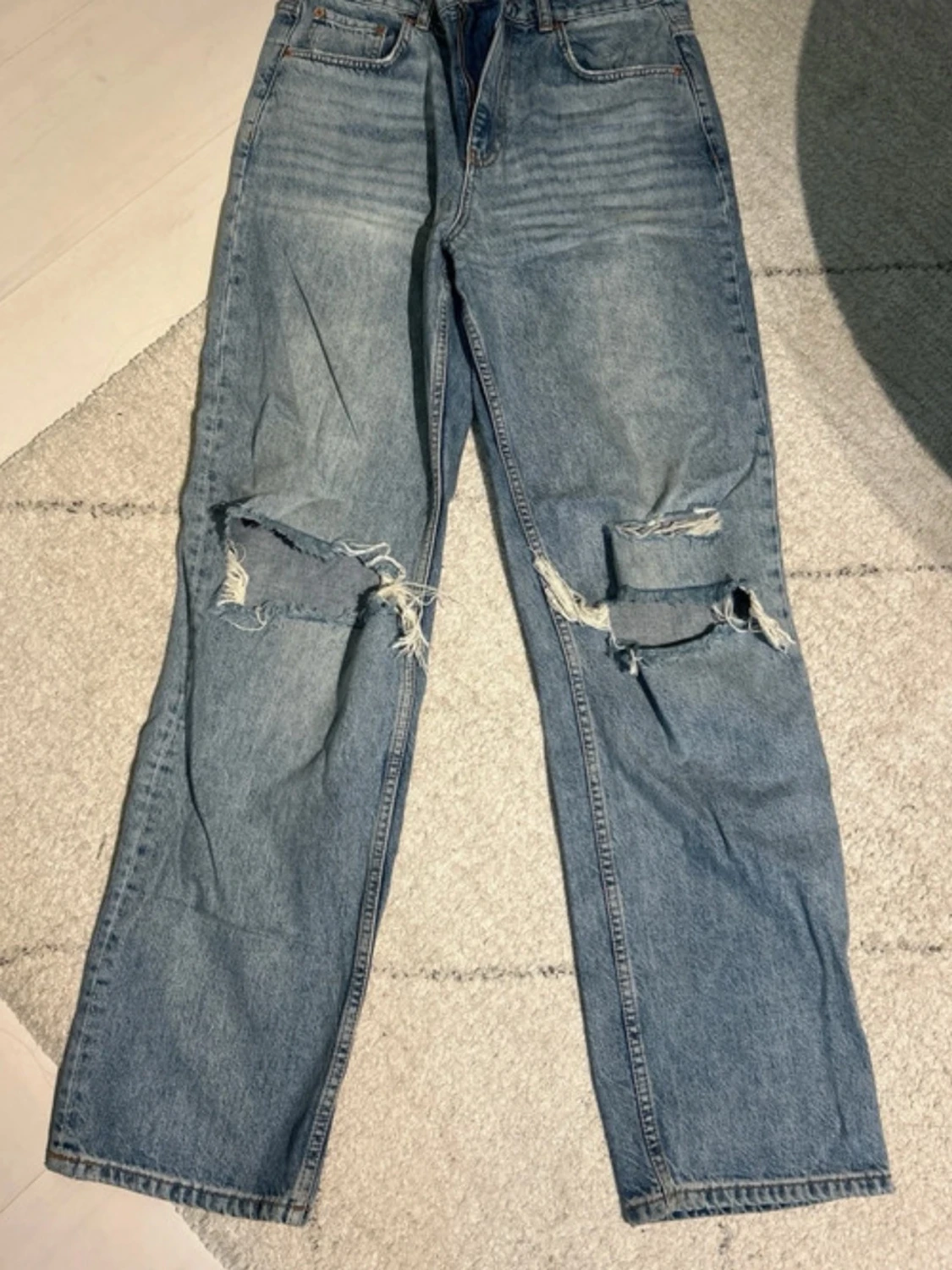 Blå slitna jeans med raka ben