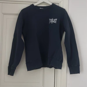 Marinblå sweatshirt - Säljer en marinblå sweatshirt från Everlast x Zara i storlek M. Tröjan har rund hals, långa ärmar och ribbade muddar vid ärmslut och nederkant. Diskret Everlast-logga på bröstet.