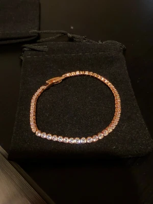 Tennisarmband - Ett elegant tennisarmband i guld med gnistrande stenar. Bästa kvalitet av zirconia,  rose guld platerad. Perfekt för både vardag och fest. Armbandet kommer i en fin presentpåse på bilden.   Liknande vara på pandora kostar 1899kr med 14k guld platering och vanlig zirconia, min vara innehåller bästa kvalitet för ett mycket mer sparsam kostnad.   Bilden innehåller en inspirations bild på en samma typ av armband på min frus arm.  Fler färger finns som gult guld 18k fråga om bilder!   2,5mm 