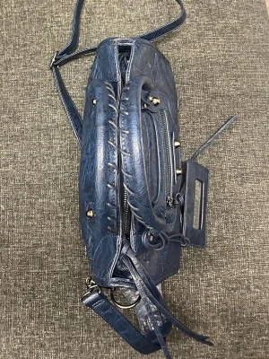 Blå Balenciaga city bag i läder - Säljer en ikonisk blå handväska från Balenciaga i läder med coola nitar, dragkedja framtill och flätade handtag. Väskan har både axelrem och handtag samt en spegel-detalj som hänger på sidan. Perfekt för dig som vill ha en statementväska med edgy vibe.