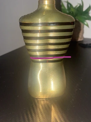 Gul randig parfymflaska torsoform - Unik parfymflaska i guld med svarta ränder, formad som en torso. Perfekt för dig som vill sticka ut med en cool och annorlunda design på hyllan. Volym, ingredienser och tillverkningsland syns ej.  