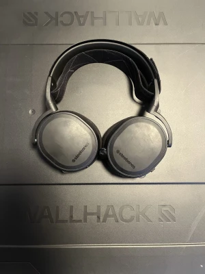 SteelSeries Arctis 7 trådlöst gamingheadset - SteelSeries Arctis trådlöst gamingheadset med tillhörande sändare. Komfortabel huvudbygel och stora öronkåpor. Några mindre repor syns på kåporna men i övrigt gott skick. Perfekt för gaming med hög ljudkvalitet och trådlös frihet.