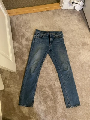 Nudie Jeans Gritty Jackson 31/34 blå - Säljer ett par klassiska blå Nudie Jeans Gritty Jackson i modellen Day Dreamer. Jeansen har raka ben, fem fickor och snygga kontrastsömmar. Tillverkade i 100% bomull för en autentisk jeanskänsla. Perfekta för dig som gillar tidlös stil.