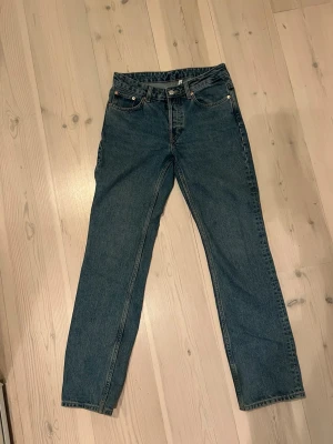 Weekday Mid Straight Jeans - Klassiska blåa Weekday jeans med rak passform. Jeansen har knappgylf, normal midja och är tillverkade i slitstarkt denimtyg. Perfekta för dig som gillar tidlös stil och vill ha ett par riktigt schyssta jeans.