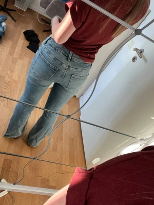 ljusblå bootcut jeans - Säljer ett par jeans i ljusblå tvätt. Klassisk bootcut-modell med medel hög midja och raka ben som släpper ut nedtill. Femficksdesign, bälteshällor och knappgylf.