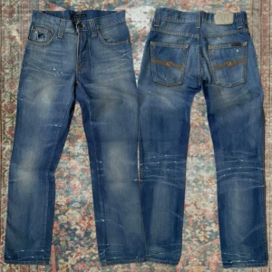 Vintage Nudie Jeans Slim Jim  - Schyssta Vintage Nudie jeans i modellen Slim Jim i mycket fint skick med snygga små slitningar ✌️ Storlek 29/32 med en loose/ regular fit. A: 38cm B: 104cm