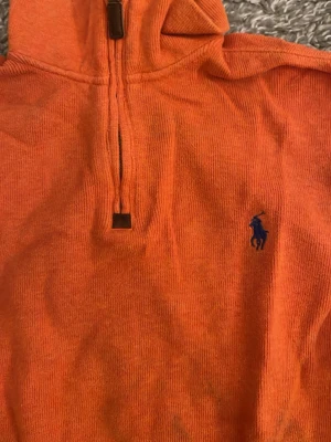 Orange manchestertröja Polo Ralph Lauren - Säljer en orange långärmad tröja från Polo Ralph Lauren i manchestertyg. Tröjan har half zip med metall-dragkedja och klassisk blå logga broderad på bröstet. Perfekt för dig som gillar färg och vill ha en chill stil.