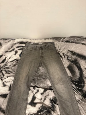 Gråa relaxed jeans från Jack & Jones - Säljer ett par gråa jeans från Jack & Jones i modellen Relaxed/Chris. De har en avslappnad passform, klassisk femficksdesign och raka ben. Jeansen är tillverkade i denim och har en snygg tvättad look som ger en cool vibe. Midja storlek är 30 och längden är 32. Jättebra skick!