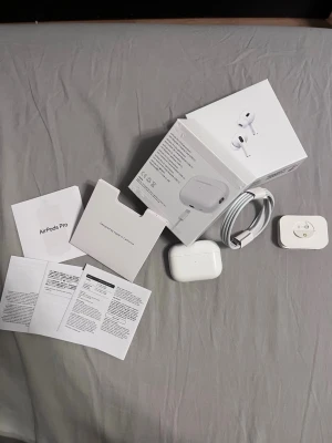 AirPods Pro (2nd generation) with MagSafe Charging Case (USB-C) - Apple AirPods Pro (2nd gen) med MagSafe-laddningsetui (USB-C). Komplett med originalförpackning, laddkabel och manualer. Produkten ser ut att vara i mycket gott skick, inga synliga defekter eller slitage. Perfekt för trådlös musik och samtal med aktiv brusreducering.