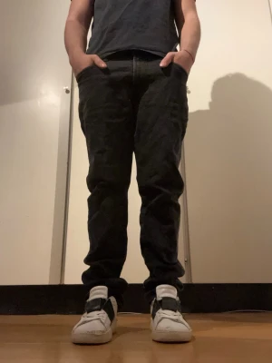 Svarta jeans med fem fickor - Svarta jeans med klassisk femficksdesign och smal passform. Jeansen har knapp och dragkedja framtill samt bakfickor. Materialet är jeans och färgen är mörk svart, vilket ger en stilren look. Perfekta för dig som gillar en tight siluett.