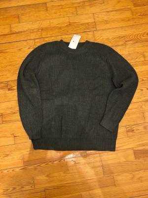 Mörkgrå stickad tröja Maison Margiela - Säljer en mörkgrå ribbstickad tröja från Maison Margiela i storlek M. Tröjan har klassisk rund hals, långa ärmar och de ikoniska vita sömmarna bak. Perfekt till lager på lager under höst och vinter.