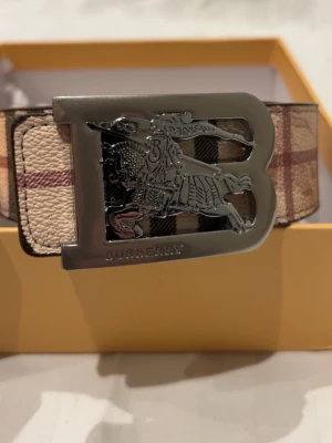 Burberry Bälte - Ett burberry bälte i bra kvalitet och skick som ligger i original kartong. Bältet är 110cm och detta passar de flesta. Bältet har två olika sidor man kan välja för att passa olika stilar. En klassisker som passar till allt. Tveka inte att skriva om du har frågor eller vill ha mer bilder.