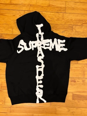 supreme hoodie - fin supreme hoodie i en svart färg med vit graphic kors på ryggen med små detaljer på designen 