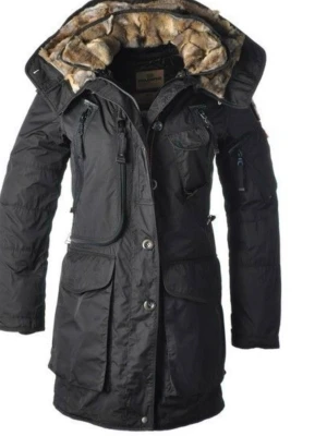 Svart parkas från Parajumpers XS - Säljer en svart Parajumpers parkas i storlek XS med fluffigt foder i huvan och flera praktiska fickor. Jackan har dragkedja och knappar framtill, samt detaljer som stora fickor och justerbar huva. Perfekt för kalla dagar och riktigt snygg streetstil.