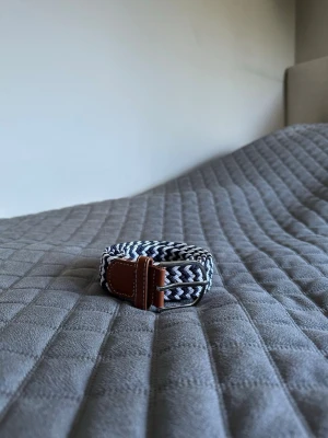 Mörkblått vit flätat bälte - Tja det är helt nytt från Bältgallerian. Det är 105cm långt och 3,5cm brett. Det är i ett elastiskt material så passar större storlekar också. Om du inte gillar den här färgen så finns det många flera att välja mellan. Vid köp av bundle så blir kostnaden billigare.