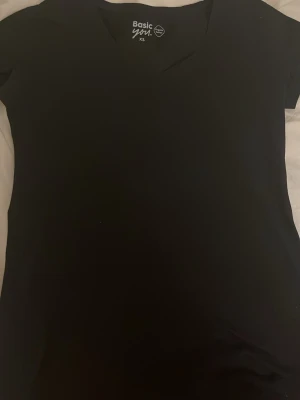 Svart basic t-shirt från Basic You - En svart basic t-shirt från Basic You i ekologisk bomull. T-shirten har v-ringning och korta ärmar, perfekt för en clean och enkel stil. Passar dig som gillar minimalistiskt och bekvämt.