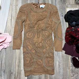 Beige spetsklänning Angelica Blick x Bik Bok - Säljer en beige kortklänning från Angelica Blick x Bik Bok i storlek XS. Klänningen har långärmad design, detaljerad spets och broderade mönster, samt dragkedja bak. Materialet känns lyxigt och strukturerat, perfekt för dig som vill sticka ut.