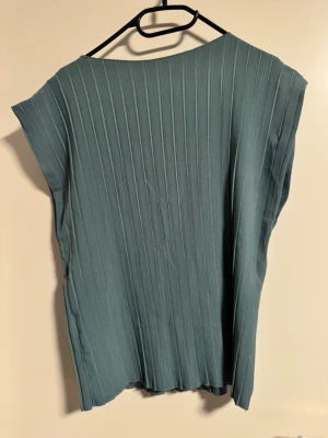 Blå ribbad topp med lös passform - Säljer en blå topp med vertikala ribbade ränder och lös passform. Toppen har breda axlar och är ärmlös, vilket ger en avslappnad och modern look. Perfekt att styla med jeans eller kjol för en enkel men snygg outfit. Hade passat M också. 