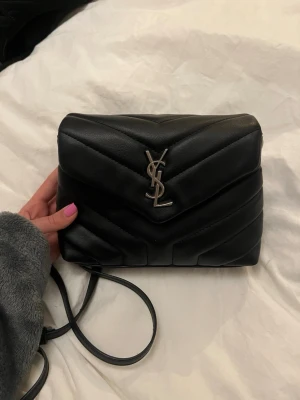 Crossbody väska  - Säljer min jätte fina väska från Saint Laurent. Väskan kommer inte till användning och är i super fint skick. Den är köpt här på plick och fick inte med något kvitto så kan därför inte garantera att den är äkta. Väskan har de stämplat den ska ha! Skriv gärna om du vill ha flera bilder❤️ pris kan diskuteras☺️