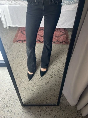 Svarta True Religion bootcut jeans - Säljer ett par svarta jeans från True Religion med bootcut passform och snygga detaljerade fickor med lock och knappar. Jeansen är midwaist. Perfekta för dig som vill ha en klassisk men edgy look. De har tappat lite färg från tvätten men fortfarande svarta och fina🩷                                               Nytt pris: 1300kr