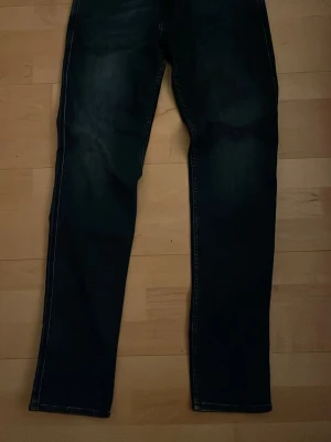 Replay Anbass slim fit jeans blå - Säljer ett par mörkblå Replay Anbass jeans i slim fit, storlek 30/32. Klassisk femficksmodell med snygga slitningar och kontrastsömmar. Jeansen har rak passform och är tillverkade i mjukt denimtyg som sitter skönt hela dagen.