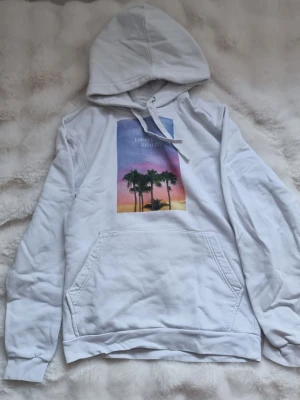 Vit hoodie med tryck - Mjuk och skön hoodie från The cool elephant men en stor magficka. Med ett fint och elegant tryck där framtill med ett litet bak.