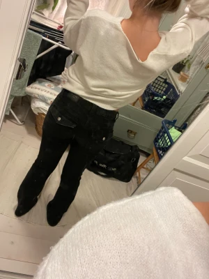 Svarta Perfect Jeans från Gina Tricot - Säljer ett par svarta Perfect Jeans från Gina Tricot i storlek 36. Modellen har låg midja, utsvängda ben och klassiska fickor med knappdetaljer bak. Anledningen för att jag säljer dem är för att jag växt ur dem