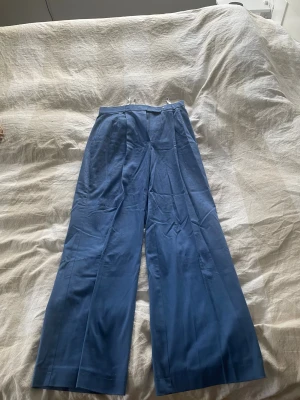 Blå wide kostymbyxor - Snygga blå kostymbyxor med wide fit och pressveck. Byxorna har hög midja och raka ben.