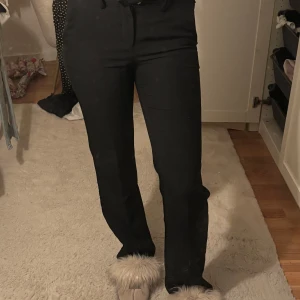 Svarta kostymbyxor från Nelly - Snygga svarta kostymbyxor från Nelly i storlek 32. Byxorna har raka ben och klassisk passform. De har fickor fram och bak samt hällor för bälte. Perfekta för en clean och stilren look. Säljer då de blivit för små. 