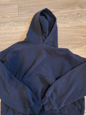 Mörkblå hoodie från Gina Tricot - Snygg mörkblå hoodie från Gina Tricot, basically basics-kollektionen. Klassisk modell med stor huva, ribbade muddar och magficka. liten olj fläck på fickan men syns knappt