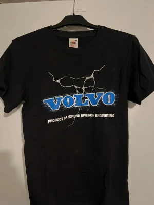 Svart Volvo t-shirt Fruit of the Loom - Svart t-shirt från Fruit of the Loom med tryck i blått och vitt där det står 'VOLVO' och 'Product of superb Swedish engineering'. Klassisk passform och rund hals, tillverkad i kraftig bomull.