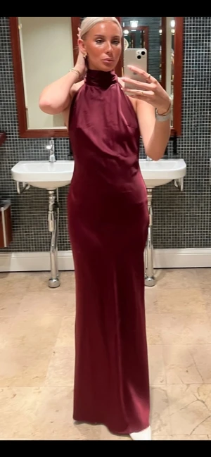 Vinröd långklänning med öppen rygg - Superfin långklänning i vinrött silke som jag hade på min bal. Aldrig använd utöver det. Den är oftast slutsåld på Boohoo’s hemsida, därför köpte jag den i storlek 40 och sydde in till en 36/38. Inga defekter och formar kroppen fint, jag har små bröst så den kan bli liiiite pösig där fram på mig. Halterneck med långt band, öppen rygg och dragkedja där bak. Går ner till marken på mig som är 175 lång. Kostar 840kr på hemsidan.