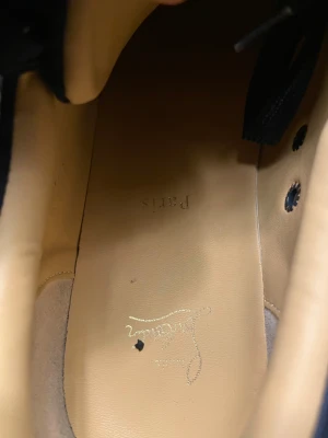 Christian Louboutin mörkblå sneakers - Snygga mörkblå sneakers från Christian Louboutin med klassisk röd sula och diskret logga på insidan. Skorna har rund tå, snörning och är tillverkade i mjuk mocka med beige skinnfoder. Perfekt för dig som vill ha en lyxig och stilren look. Dusbag tillkommer..!!! Och box !!! Kommer göra rent de ora er inte 