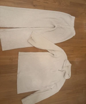 Beige ribbade stickade tvådelad set  - Säljer ett par beige stickade byxor med ribbad struktur. Byxorna   har en rak och loose passform med elastisk midja för extra komfort. Perfekta för chill dagar hemma eller när du vill vara extra cozy. Materialet är mjukt och värmande.