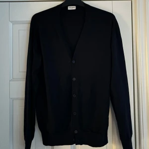 John Henric kofta - Sprillans ny oanvänd svart John Henric Kofta i storlek L men sitter 100% som M säljes. Den är av högsta kvalite finstickad av 100% merinoull. Sjukt snygg och skicket är som sagt 10/10! Färgen är typ svart/väldigt mörk blå. Tveka inte vid minsta fråga eller fundering😃