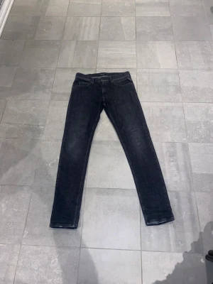 Replay svarta jeans slim fit - Snygga svarta jeans från Replay med klassisk femficksdesign och smal passform. Jeansen har en mörk tvätt och raka ben, tillverkade i mjukt jeanstyg med stretch för extra komfort. Perfekt för dig som gillar stilrena och tidlösa jeans.
