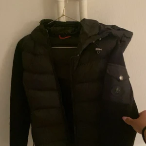 Moncler Jacka  - Svart pufferjacka från Moncler med huva och dragkedja framtill. Säljs för kommer ej till användning.