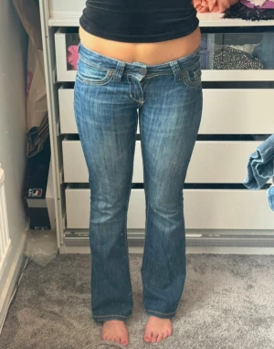 Blå bootcut jeans med låg midja - Snygga blå jeans från A&F med låg midja och bootcut passform. Mina absoluta favoritjeans som blivit för små. Det tar verkligen emot att sälja dessa, de sitter så snyggt och är så bekväma. Midjemått: 38cm. Innerbenslängd: 76,5.