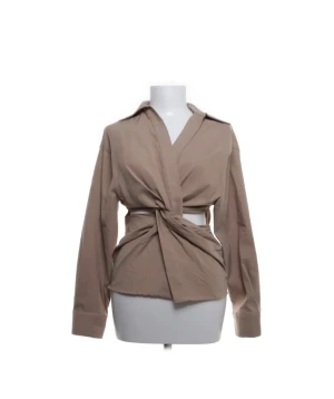 Beige omlottblus från Zara - Stilren beige skjorta från Zara med omlottknytning i midjan och klassisk krage. Långärmad modell i mjuk bomull, perfekt för en trendig och avslappnad look. Snygg detalj med breda manschetter och knappar vid ärmslut❤️❤️