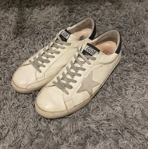 Golden Goose Superstar - Säljer nu dessa riktigt snygga sneakers från Golden Goose!  De är i bra skick men hälarna och sulan är sliten, se bilder, men inget som syns vid användning. Storlek 43.  Nypris runt 4000kr!  Självklart äkta✔️ Hör av dig vid frågor eller funderingar, priset är inte hugget i sten!