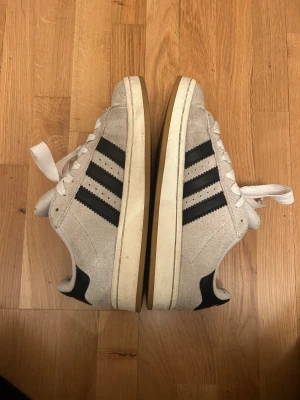 Adidas Campus sneakers i beige mocka - Säljer ett par Adidas Campus sneakers i beige mocka med klassiska svarta ränder på sidorna fint skick vid köp rengörsdem såklart noggrant 