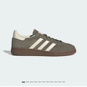 Adidas Spezial sneakers i mocka - Snygga Adidas Spezial sneakers i olivgrön mocka med klassiska vita ränder och detaljer. Skon har brun sula, snörning och guldfärgad Spezial-logga på sidan. Perfekt för dig som gillar retrostil och streetwear. Endast använda en gång och säljer då de inte passade mig.