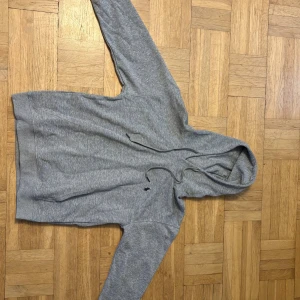 Grå hoodie från Polo Ralph Lauren - Snygg grå hoodie från Polo Ralph Lauren med klassisk broderad logga på bröstet. Tröjan har huva med snörning och ribbade muddar vid ärmslut och nederkant. Perfekt för chill dagar och enkel att matcha med jeans eller joggers.