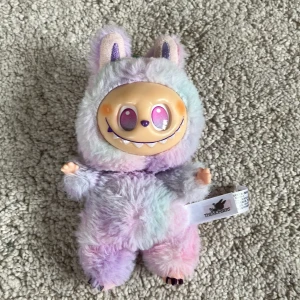 THE MONSTERS Plush Doll (Lafufu) ❤️ - Söt och unik THE MONSTERS mjukisdocka. Dockan har ett färgglatt, fluffigt pälsöverdrag i pastellfärger och ett glatt ansikte med stora ögon. Skicket är mycket bra, inga synliga defekter eller slitage. Perfekt för samlare eller som present! ❤️