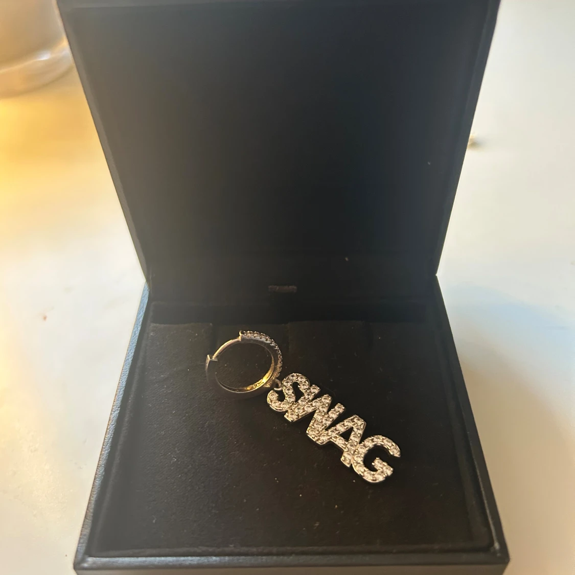 Glittrig örhänge med SWAG-text