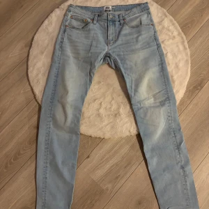 Ljusblå jeans från 157, storlek L - Säljer ett par ljusblå jeans från 157 i storlek L. Modellen har klassisk femficksdesign, raka ben och normal passform. Jeansen är tillverkade i mjukt denimtyg med snygga slitningar och kontrastsömmar. Perfekt för dig som gillar en avslappnad och stilren look.