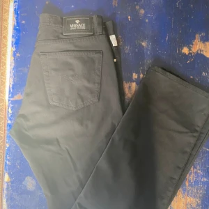 Svarta jeans - Svarta jeans med klassisk femficksdesign, silverfärgade detaljer och logotyp på bakfickan och knappen. Snyggt rak passform och tillverkade i slitstarkt bomullsmaterial. Perfekta för dig som gillar exklusiv streetstyle. Nyskick w28 L32