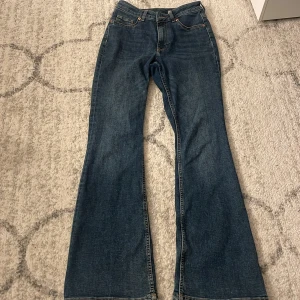 Blå bootcut jeans från Levi's - Säljer ett par klassiska blå jeans från Levi's med bootcut passform. Jeansen har fem fickor, knapp och dragkedja framtill samt snygga kontrastsömmar. Perfekt för dig som gillar retrovibbar och vill ha ett par jeans med lite vidare ben.