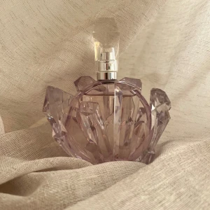 Ariana Grande R.E.M.  - En helt underbar doft av Ariana Grande, 100ml (se använd mängd på bild) Toppnoter: Kvitten, fikon, salt karamell och marshmallow. Hjärtnoter: Lavendel och päronblom. Basnoter: Tonkaböna, mysk och sandelträ. Säljes utan box. Förvarats mörkt och svalt. 
