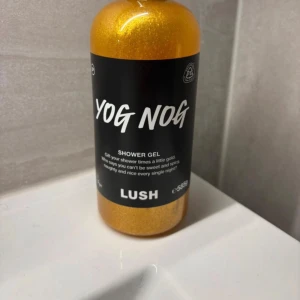 Yog Nog shower gel från Lush - Yog Nog shower gel från Lush i en glittrande gyllene färg. Kommer i en rund plastflaska med svart etikett och vitt tryck. Perfekt för dig som älskar söta och kryddiga dofter med extra shimmer.